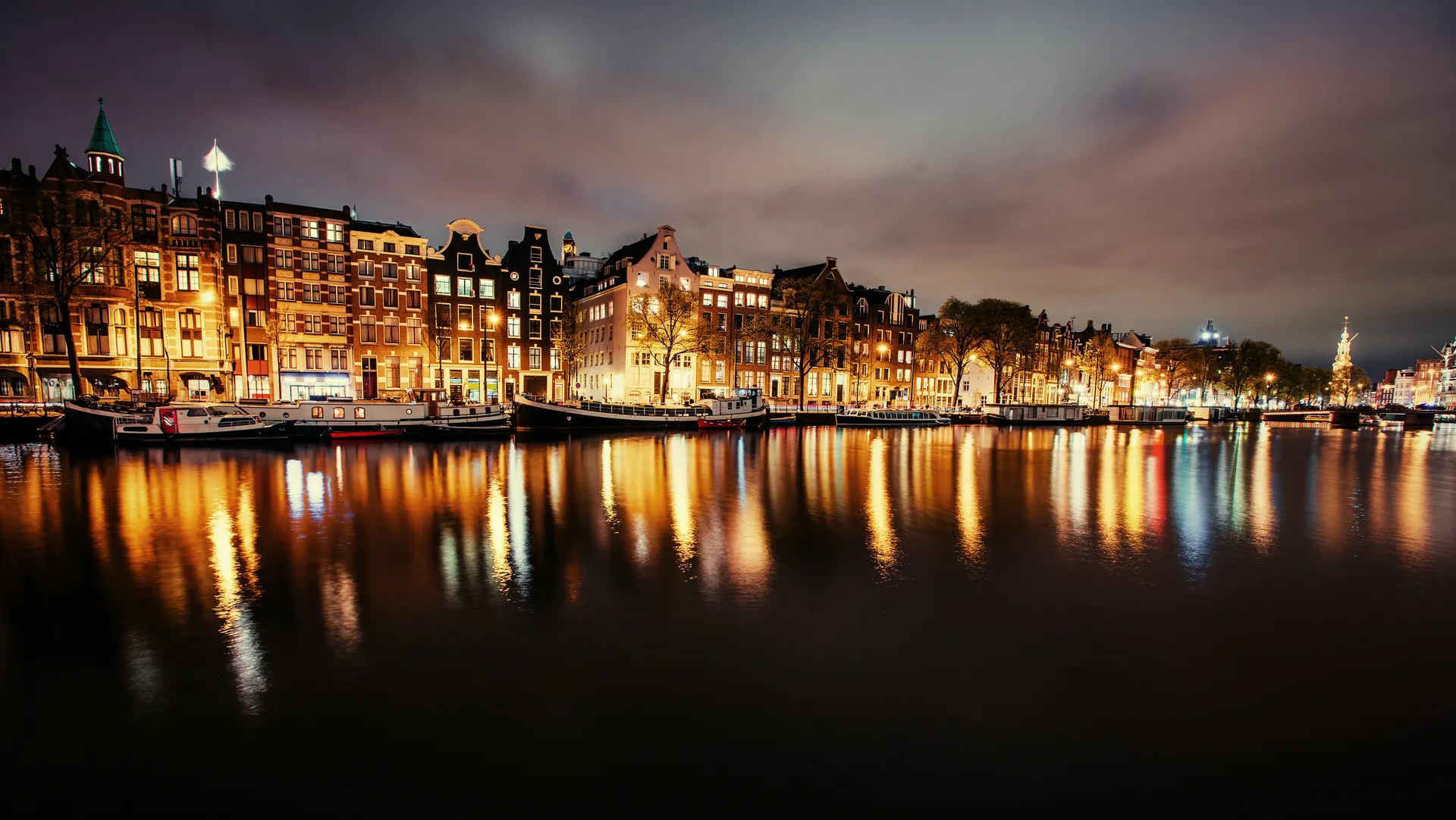 Canal houses illuminated at night, reflected in dark water