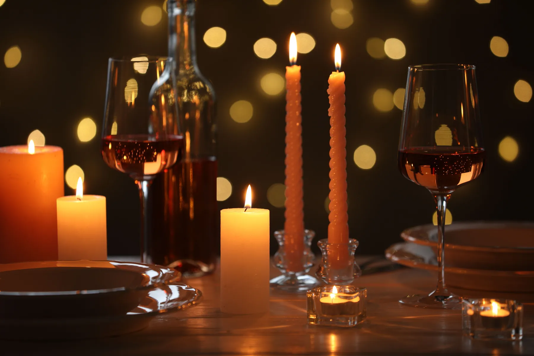 A candlelit place setting with wine glasses and warm bokeh lights