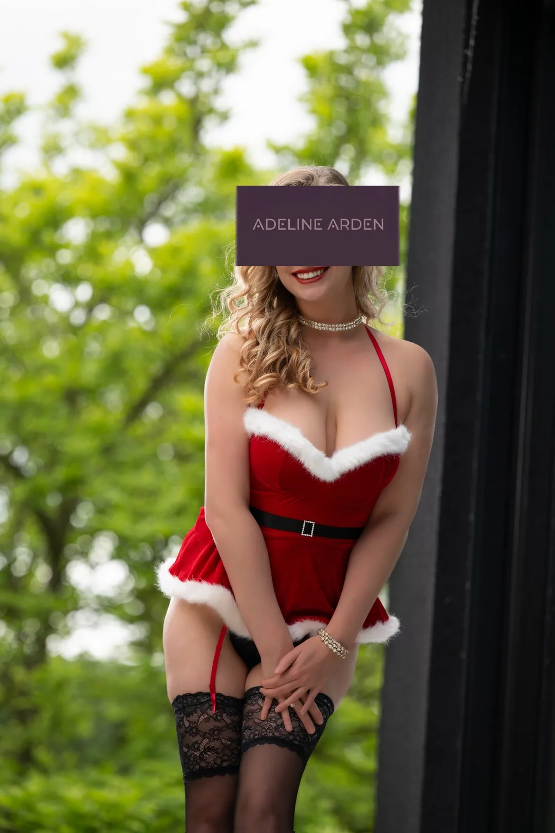 Adeline in a red festive outfit with white trim and lace stockings
