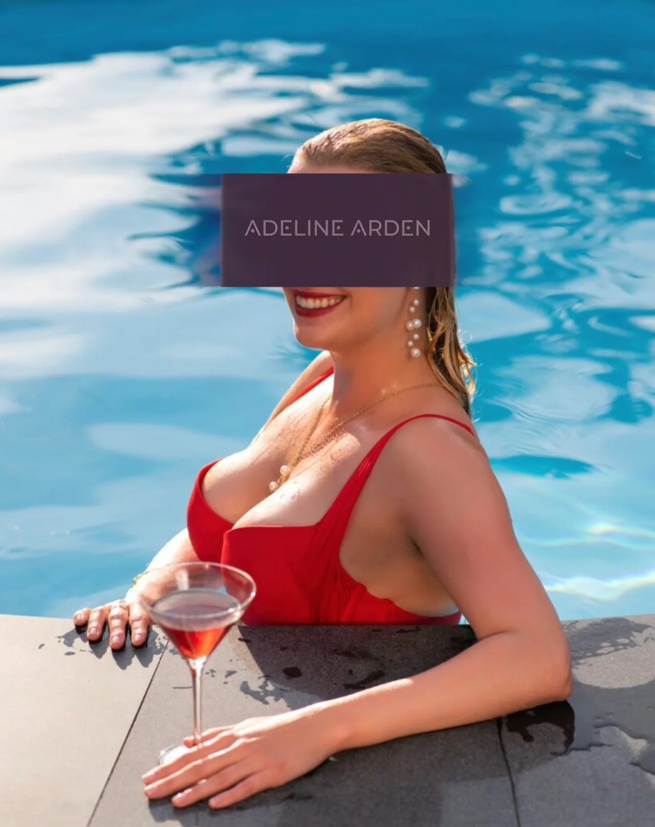 Adeline in a red bikini holding a cocktail beside a pool